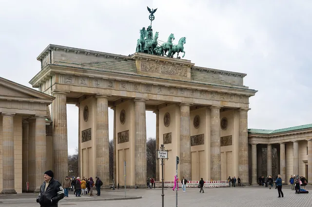 The sandstone columns of the Brandenburg Gate in Berlin topped by the Quadriga statue under a pale sky