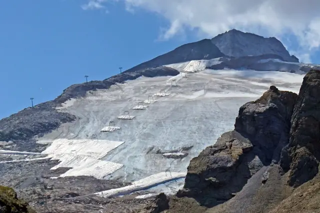 Snow-covered slopes and ski lifts on the Hintertux Glacier beneath a rocky summit