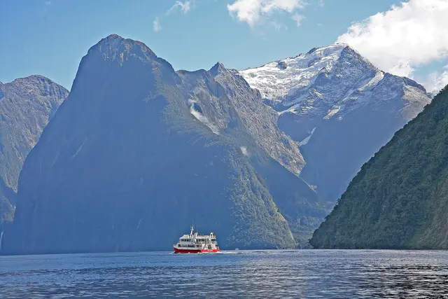 A cruise boat on Milford Sound beneath the steep peaks of Fiordland, with snow on the higher summits