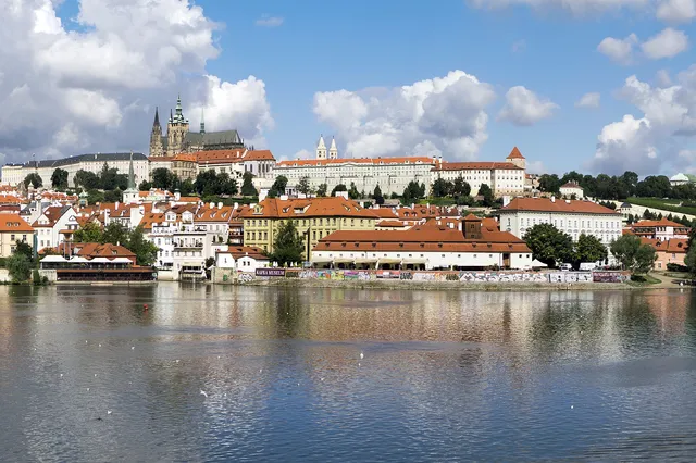 Prague Castle and the spires of St Vitus Cathedral on the hill above red rooftops and the Vltava river