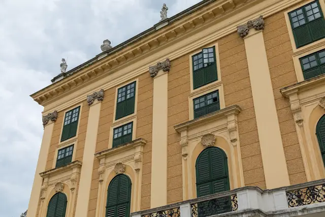 The yellow façade of Schönbrunn Palace with tall green-shuttered windows