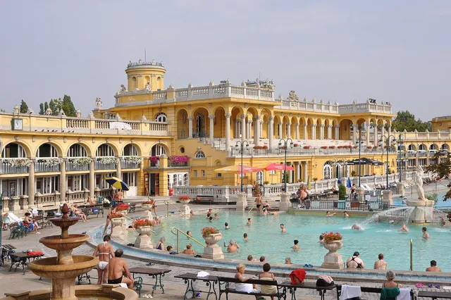 Bathers in the outdoor thermal pool at Széchenyi Baths surrounded by yellow neo-Baroque buildings and domes