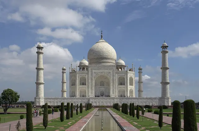 The white marble Taj Mahal and its four minarets, reflected in the long water channel of the Mughal gardens