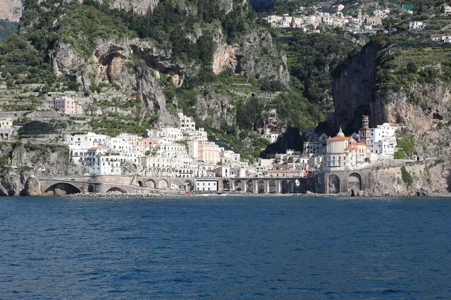 The white houses and domed church of Atrani tucked into a cliffside valley above the sea on the Amalfi Coast