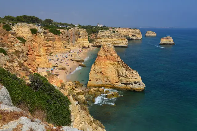 Golden limestone cliffs, rock stacks and a small sandy cove at Praia da Marinha in the Algarve, Portugal