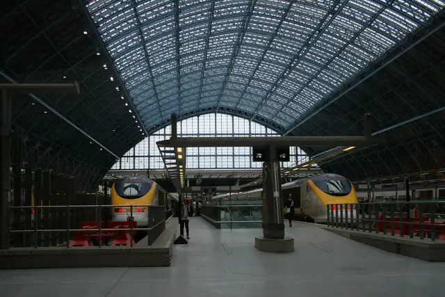 Two Eurostar trains waiting at the platforms under the glass roof of London St Pancras International station