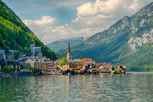 The lakeside village of Hallstatt with its church spire beneath wooded mountains, seen from Lake Hallstatt