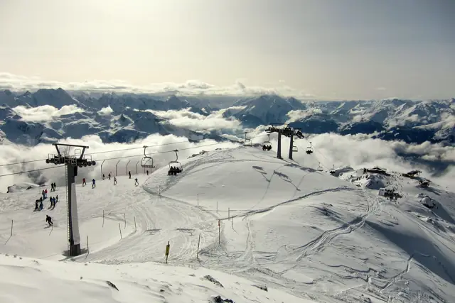 Skiers on a snowy slope beside a chairlift above a sea of clouds in the Zillertal, Tyrol