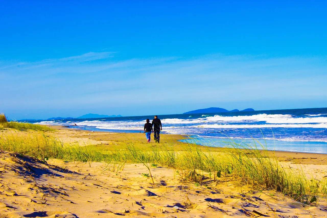 Casal de idosos caminhando pela praia