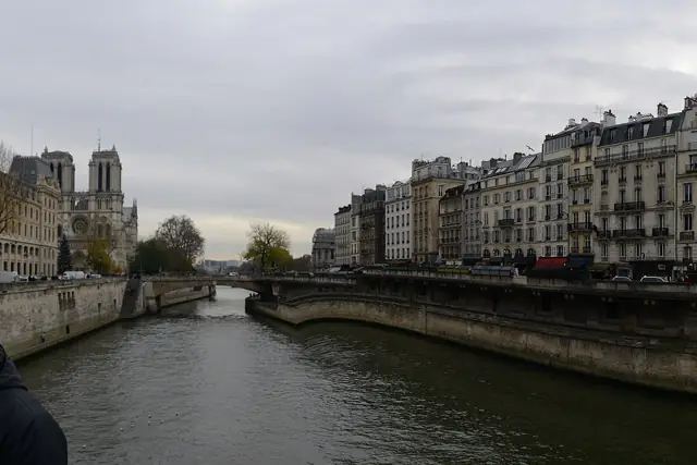 The River Seine in Paris lined with stone quays and Haussmann buildings, with Notre-Dame Cathedral in the distance