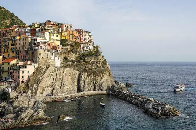 Colourful houses of Manarola stacked on a rocky headland above the harbour in the Cinque Terre, Italy