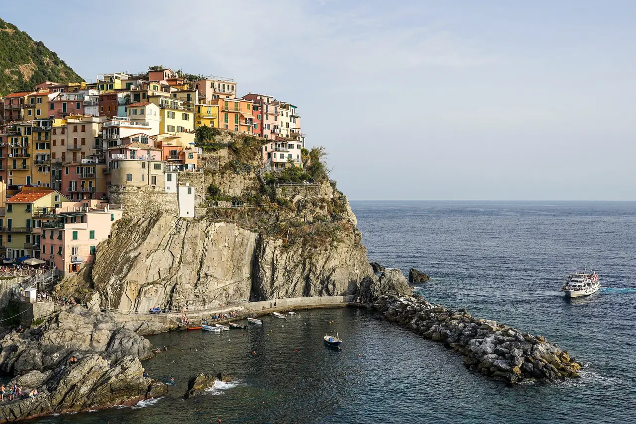 Colourful houses of Manarola stacked on a rocky headland above the harbour in the Cinque Terre, Italy