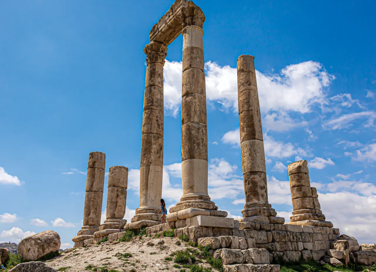 The surviving columns of the Roman Temple of Hercules on the Amman Citadel under a blue sky with white clouds