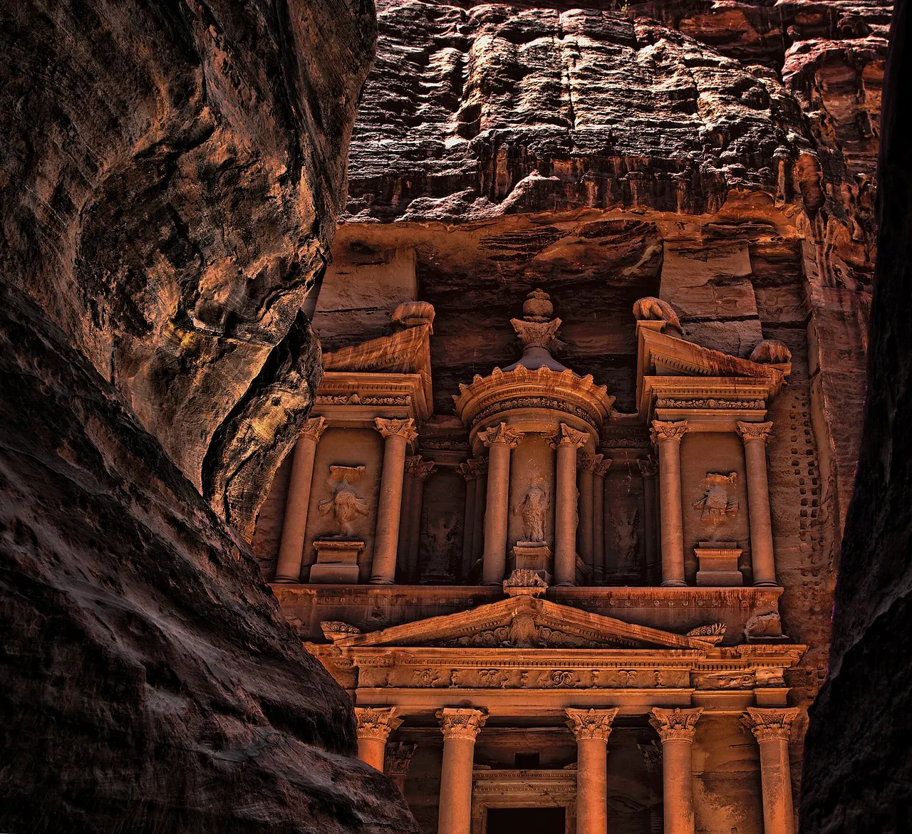 The rose-red rock-cut façade of the Treasury at Petra, seen from the end of the Siq