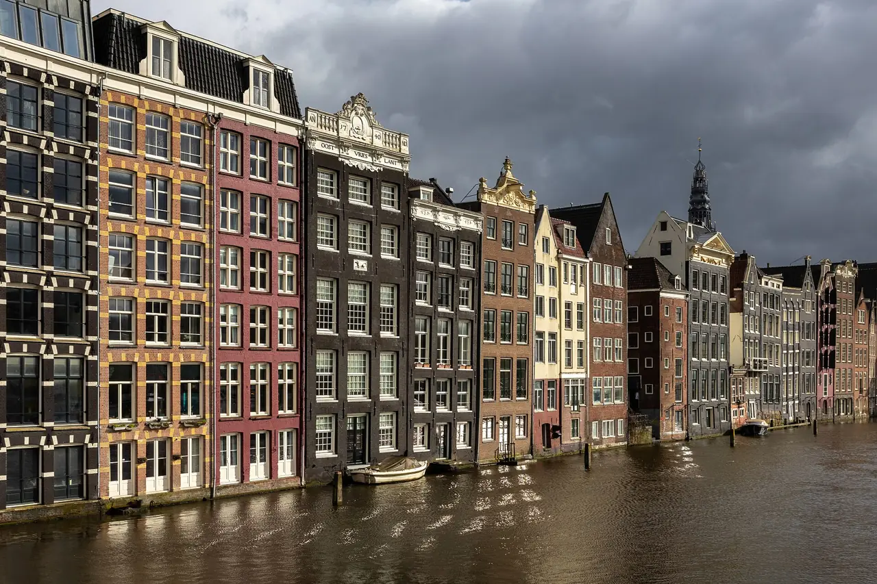 Colourful gabled canal houses on the Damrak waterfront in Amsterdam at golden hour