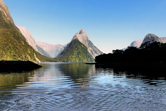 Mitre Peak and the steep green mountains of Milford Sound reflected in the calm water of the fiord