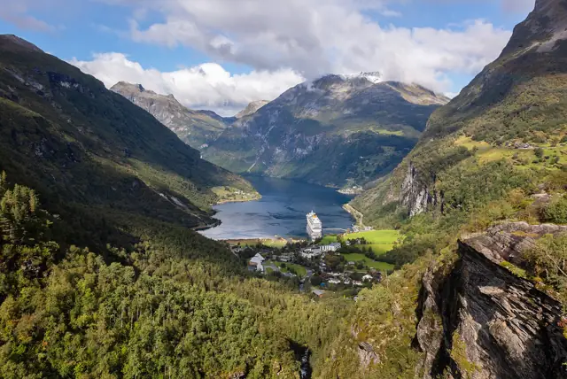 The Geirangerfjord winding between steep green mountains, seen from the Flydalsjuvet viewpoint above Geiranger