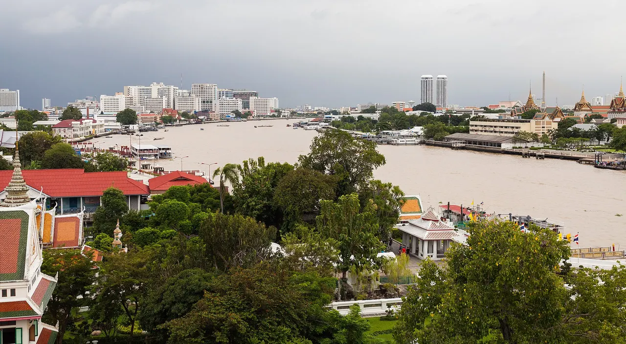 Boats on the Chao Phraya River in Bangkok, with the city skyline along the riverbank