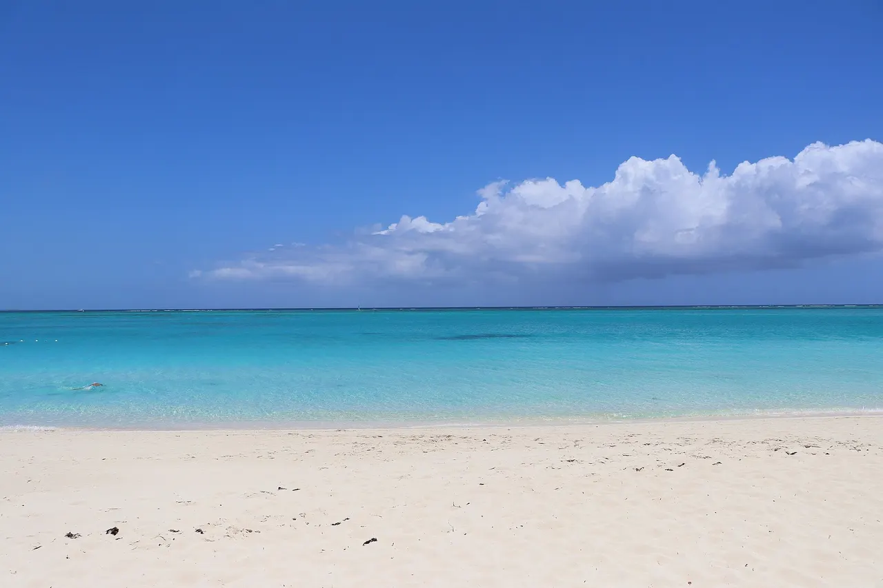 Grace Bay Beach facing north with some clouds in the distance at the horizon. Photographed by user Coolcaesar on May 25, 2025