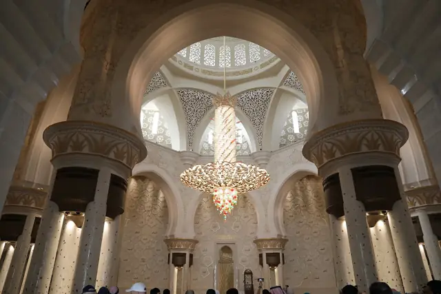 The vast white marble prayer hall of the Sheikh Zayed Grand Mosque in Abu Dhabi with a huge crystal chandelier and gilded columns