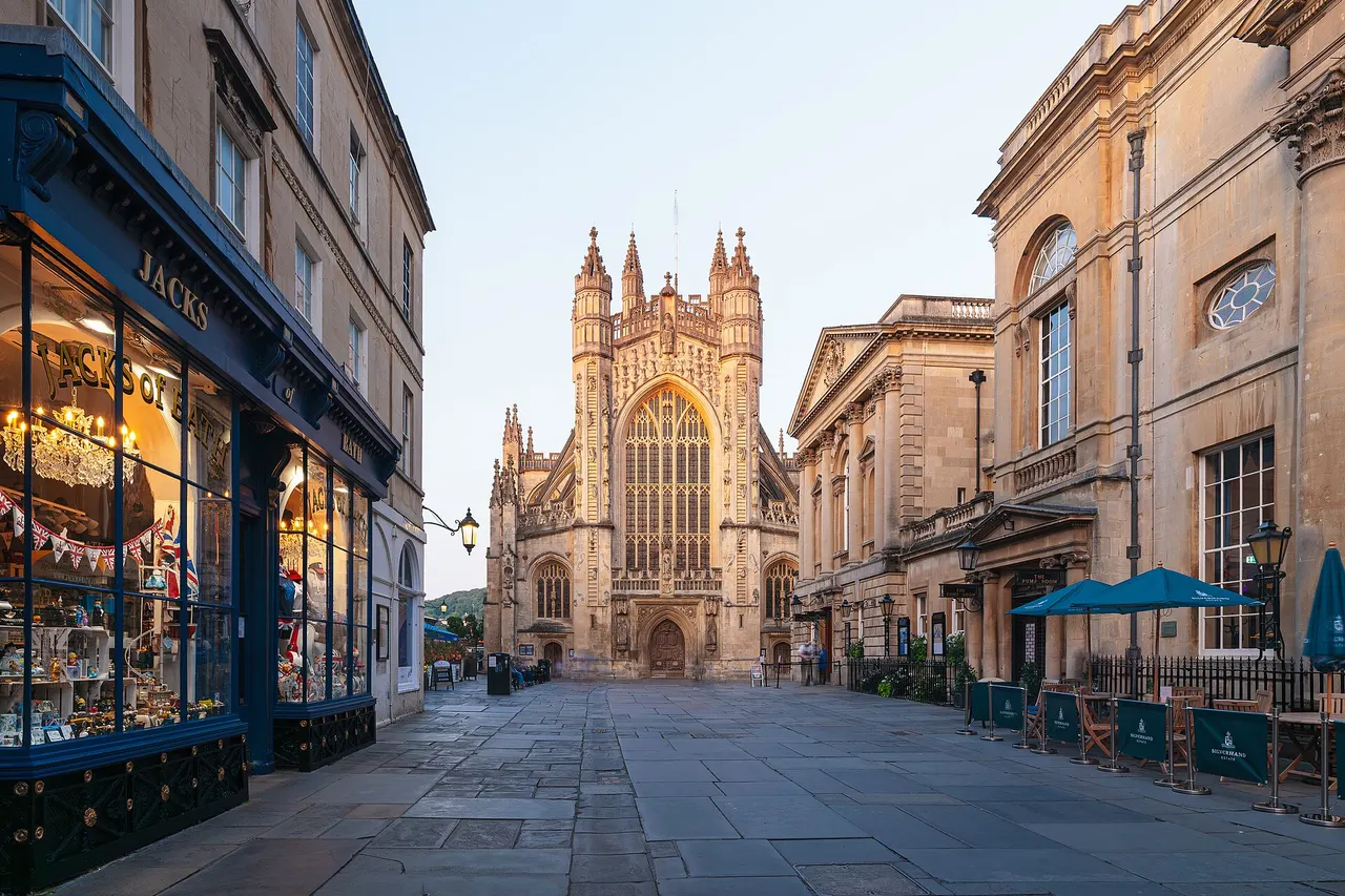 Bath Abbey, view from the west with the Roman Baths on the right, in evening light. This is a photo of listed building number 1394015