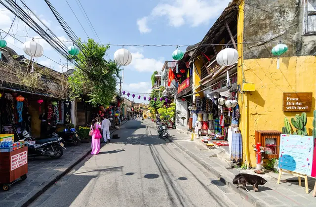 Lanterns strung across a street of yellow-walled shophouses in the Ancient Town of Hoi An, Vietnam